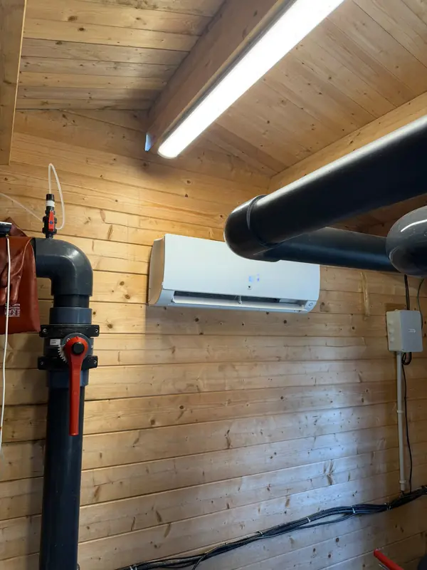 Climatiseur mural dans le local technique piscine en bois